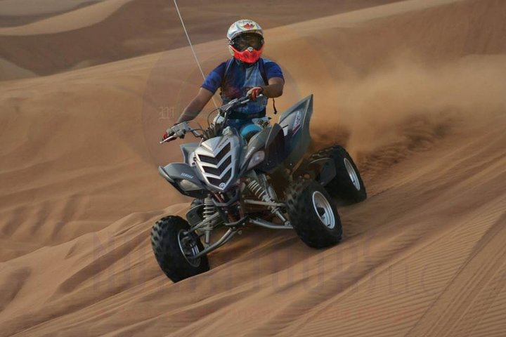 Experience the excitement of conquering sand dunes on a quad bike feeling the rush of the desert wind as you navigate thrilling twists and turns across the golden landscape.